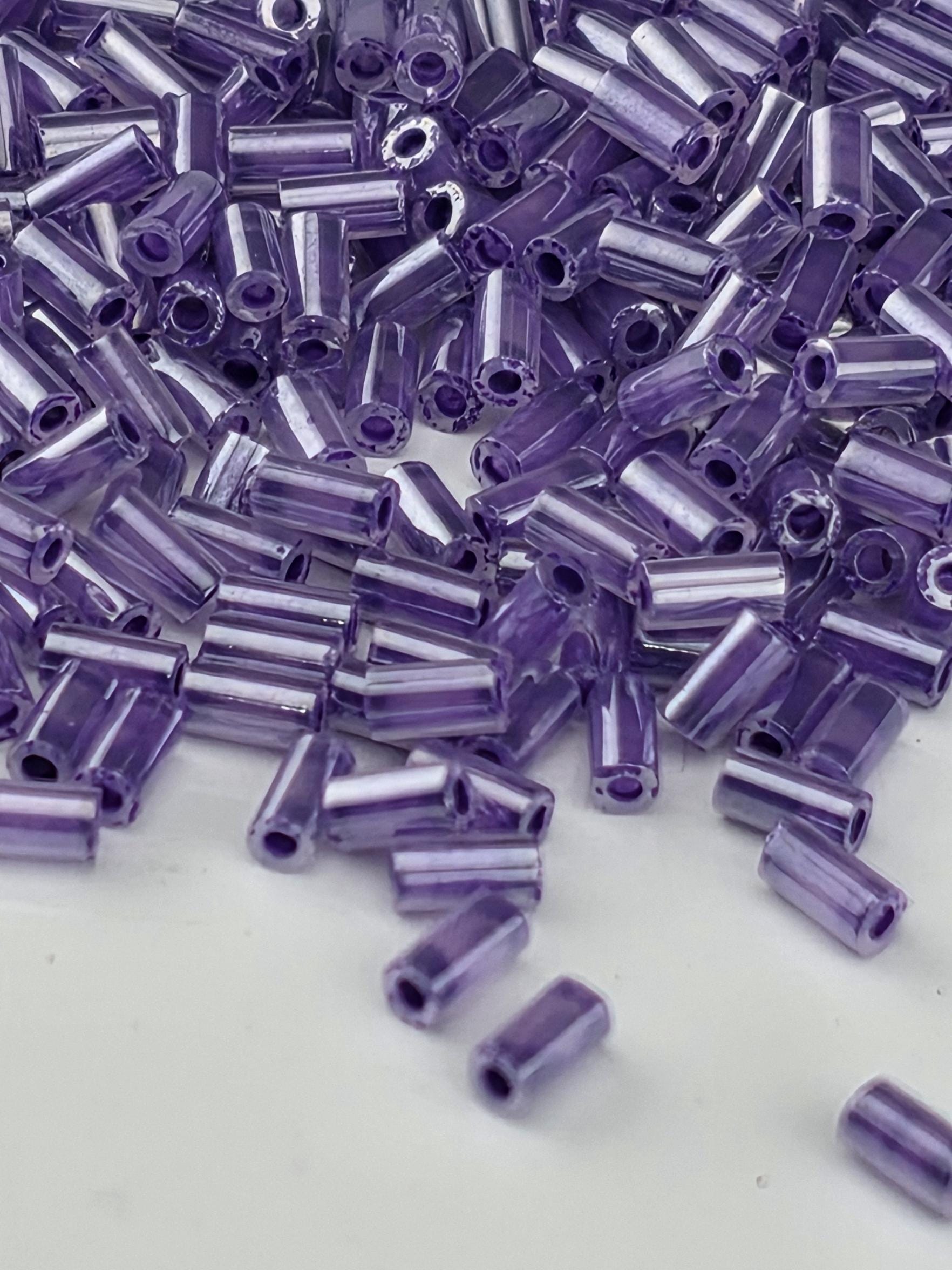 A close-up image of numerous small, clear beads in a vibrant shade of purple.