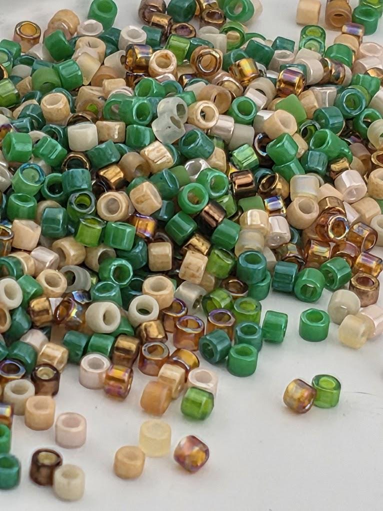 A pile of multicolored beads, including green, brown, and beige, scattered on a white surface.