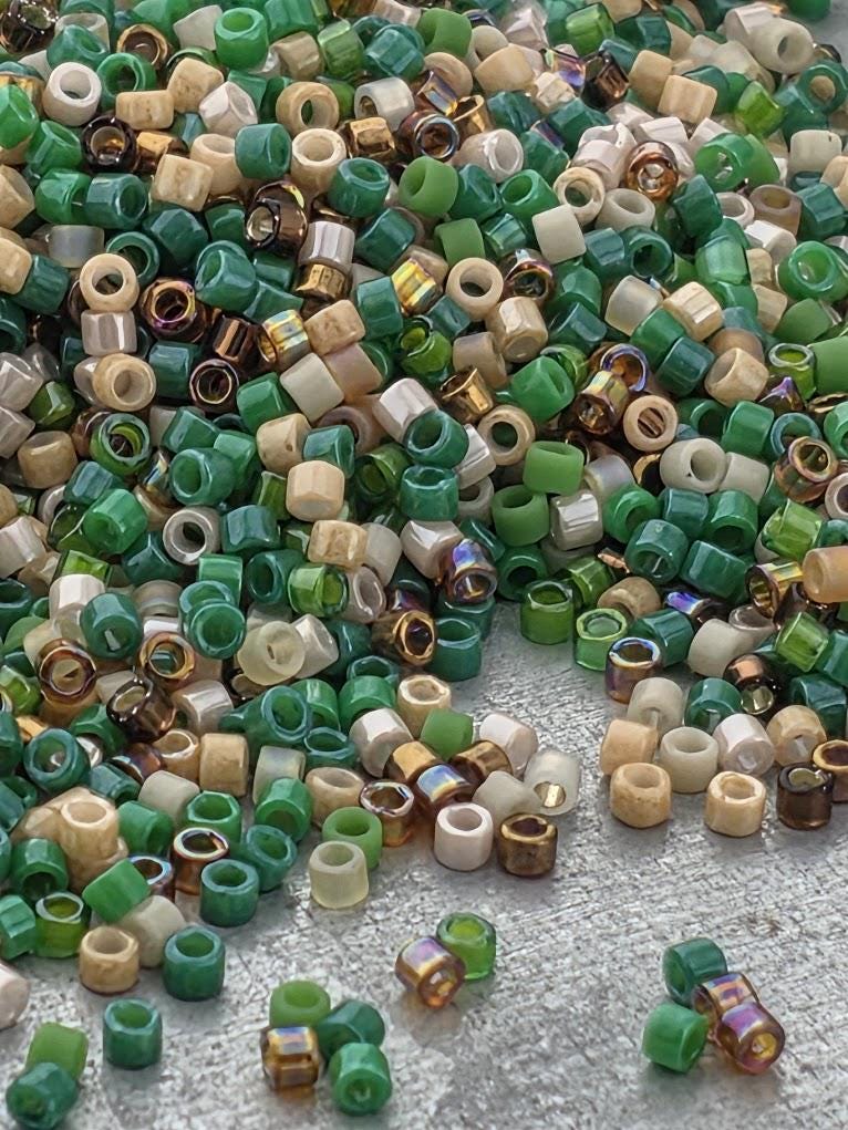 A pile of colorful beads in various shades of green, beige, and brown, scattered on a surface.
