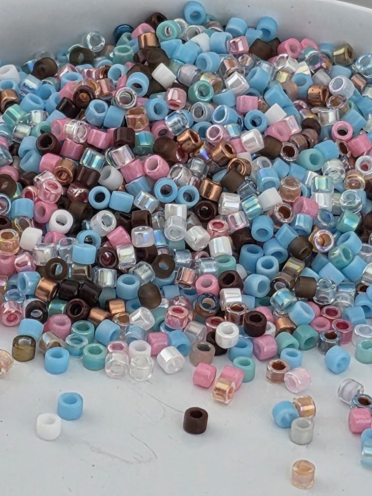 A pile of multicolored beads, including various shades of blue, pink, and brown, scattered on a surface.