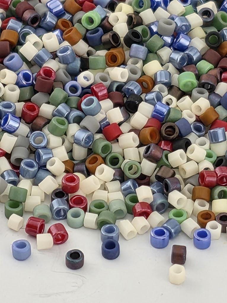 A colorful pile of multicolored beads, including various shades of blue, green, red, and white, scattered across a surface.