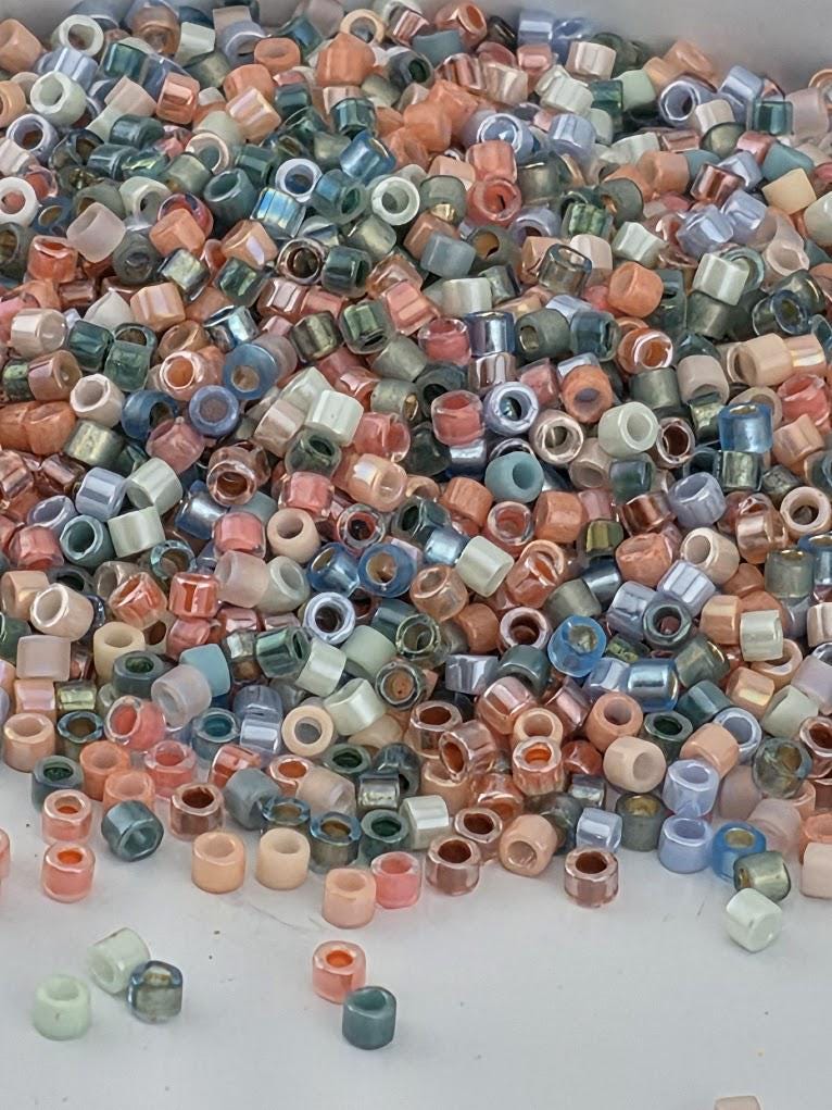 A large pile of multicolored beads, including various shades of blue, green, orange, and pink, scattered on a surface.