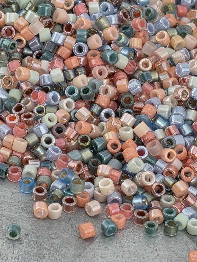 A large pile of multicolored beads, including various shades of blue, green, orange, and pink, scattered on a surface.