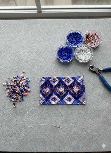 a crafting workspace with various beads, thread, and tools, including a pair of scissors, arranged on a gray surface.