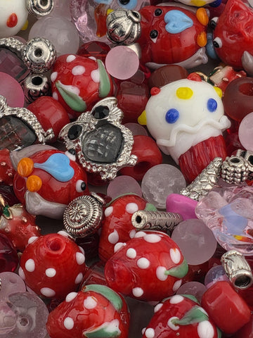 The image is a close-up of a collection of colorful beads, charms, and other small objects, including a white and yellow object resembling a clown, red and white polka dot objects, and various other shapes and designs.