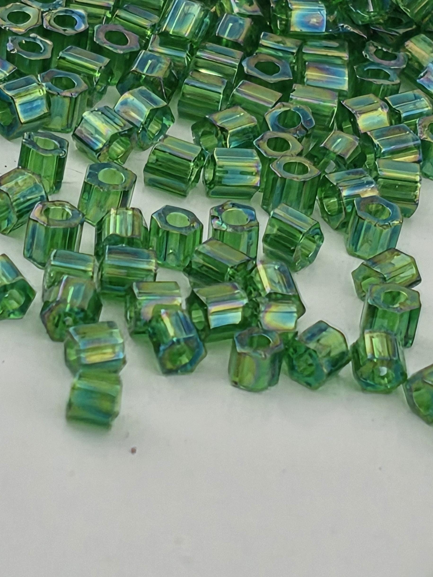 a close-up view of numerous green glass beads scattered across a white surface.