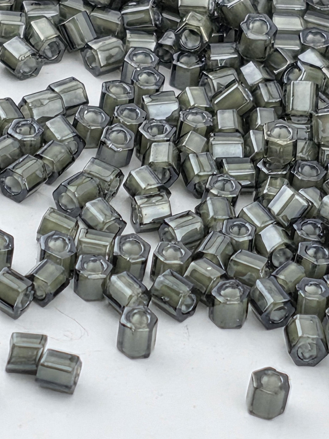 a large pile of small, square-shaped objects with a dark gray or black color, scattered on a white surface.