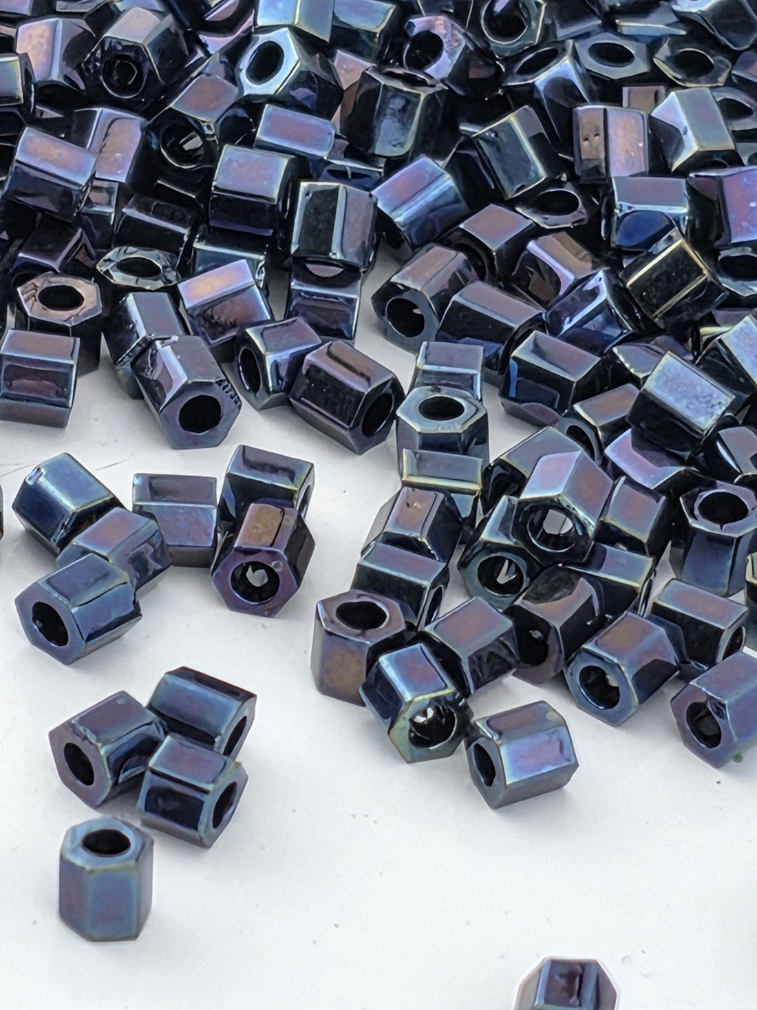 a pile of small, shiny metal nuts and bolts scattered on a white surface.