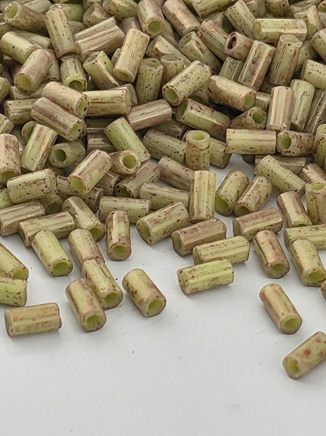 a pile of small, cylindrical objects with a speckled or speckled appearance, scattered on a white surface.