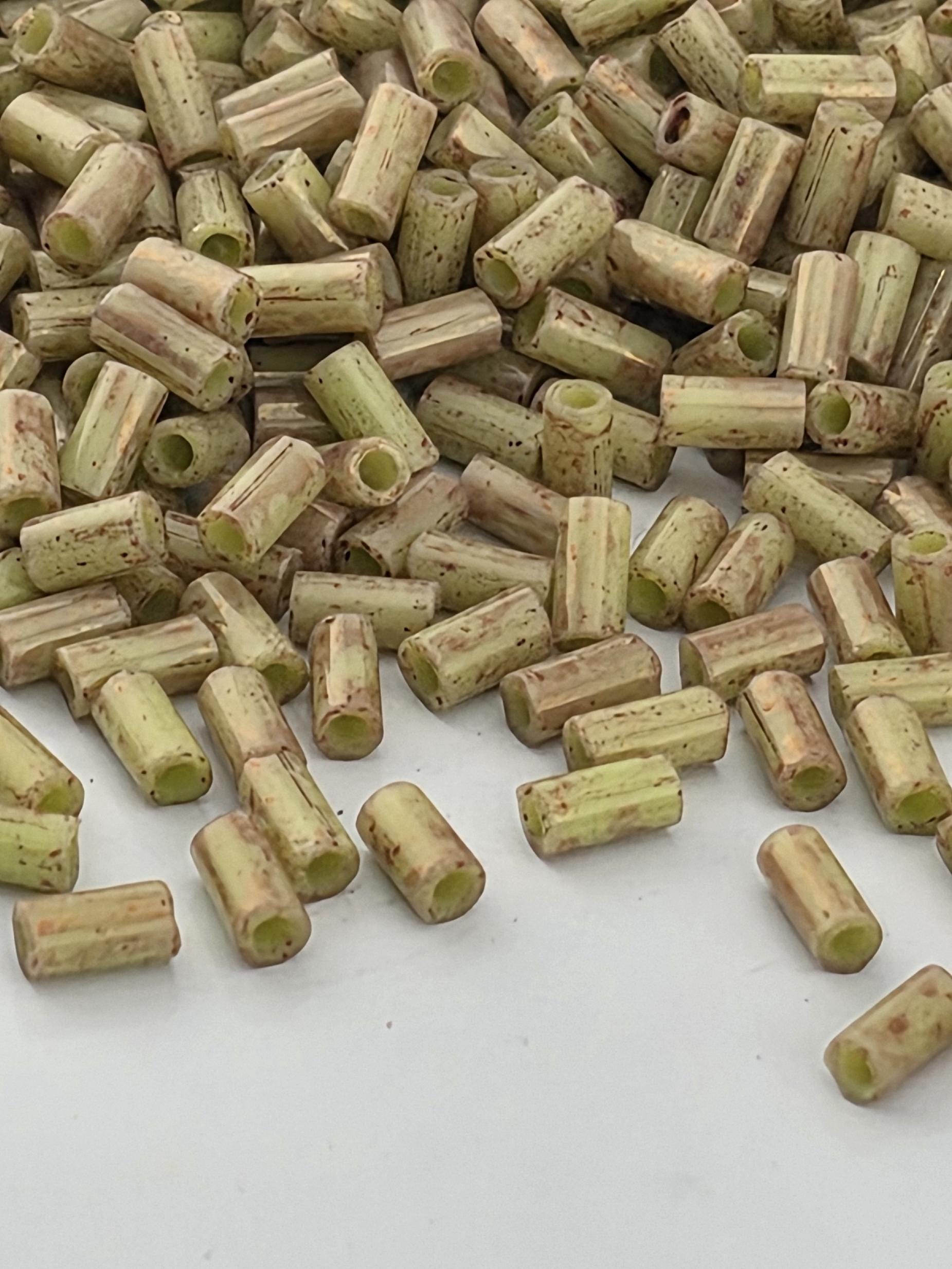 a pile of small, cylindrical objects with a speckled or speckled appearance, scattered on a white surface.