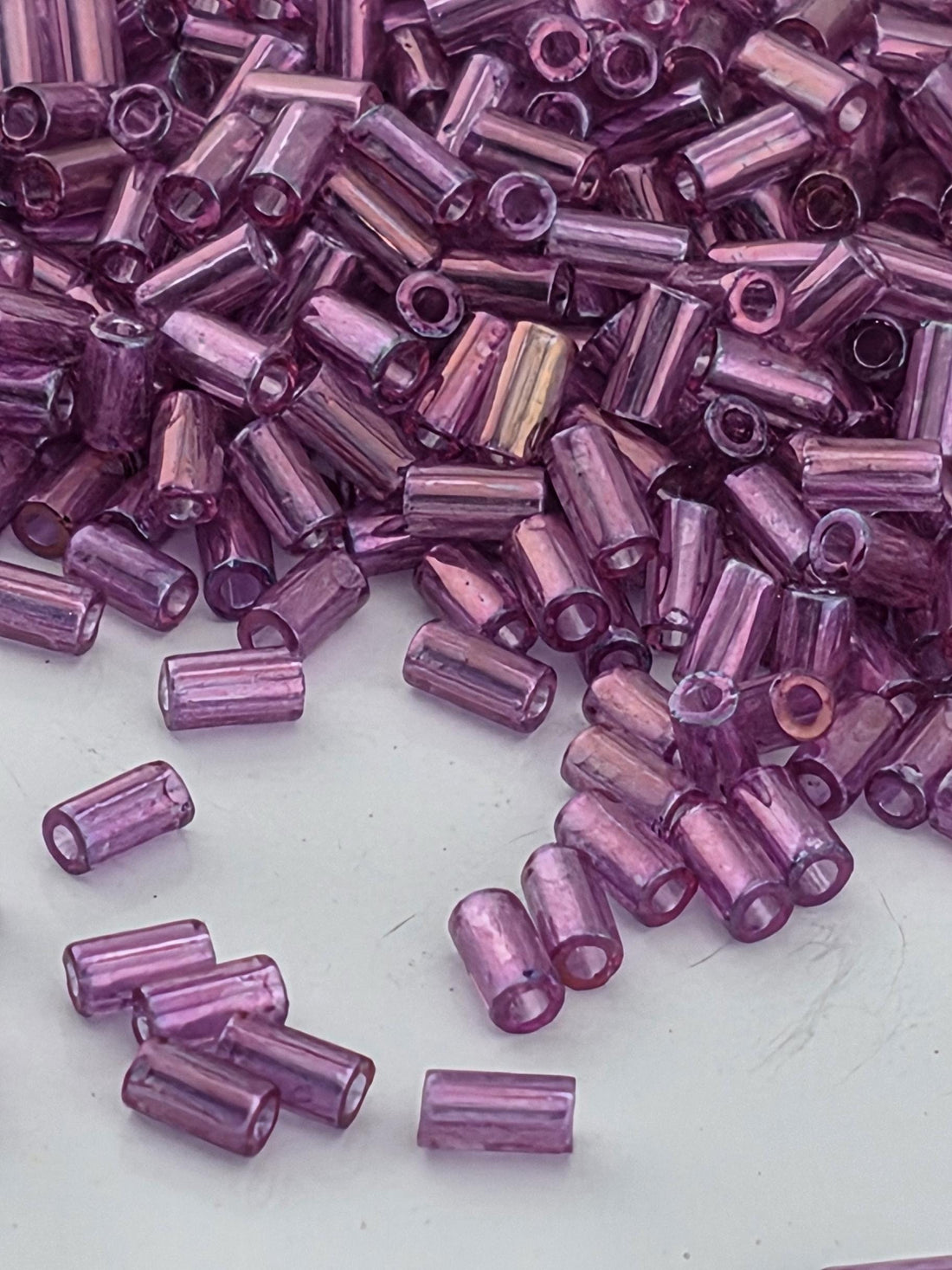 a close-up view of numerous small, purple beads scattered across a white surface.