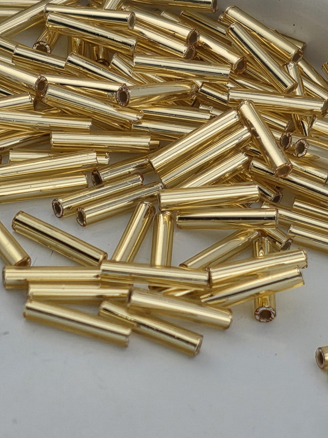 numerous gold-colored metal tubes or rods, which appear to be arranged in a pile or scattered across a surface.