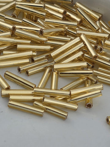 numerous gold-colored metal tubes or rods, which appear to be arranged in a pile or scattered across a surface.