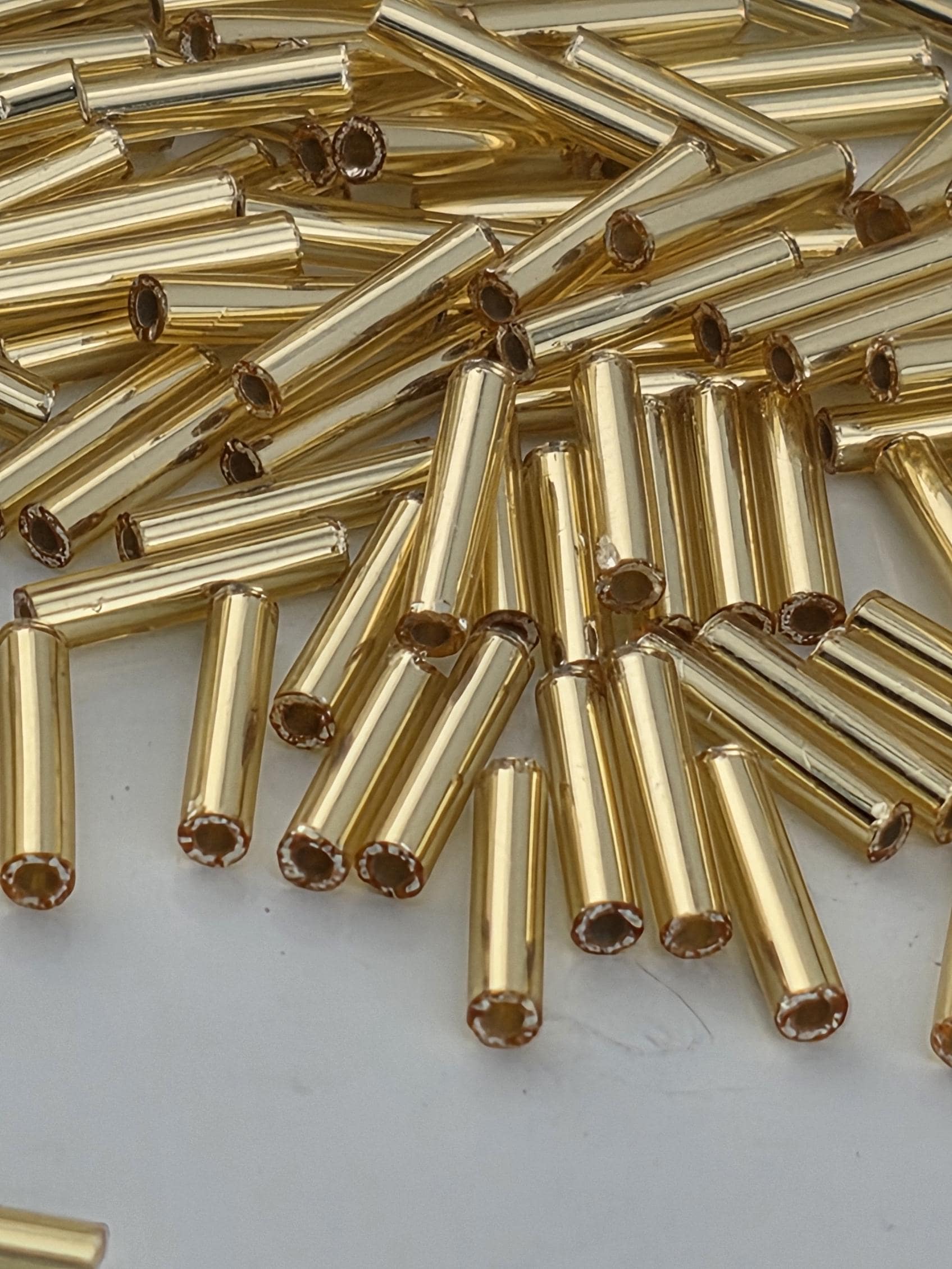 a close-up view of numerous gold-colored metal tubes or rods scattered across a surface.