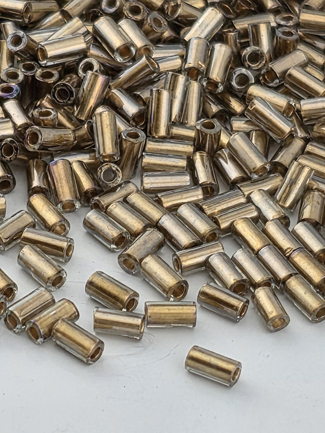 numerous small, cylindrical objects that appear to be made of a shiny, metallic material. They are scattered across a surface, creating a visually interesting and somewhat chaotic arrangement.