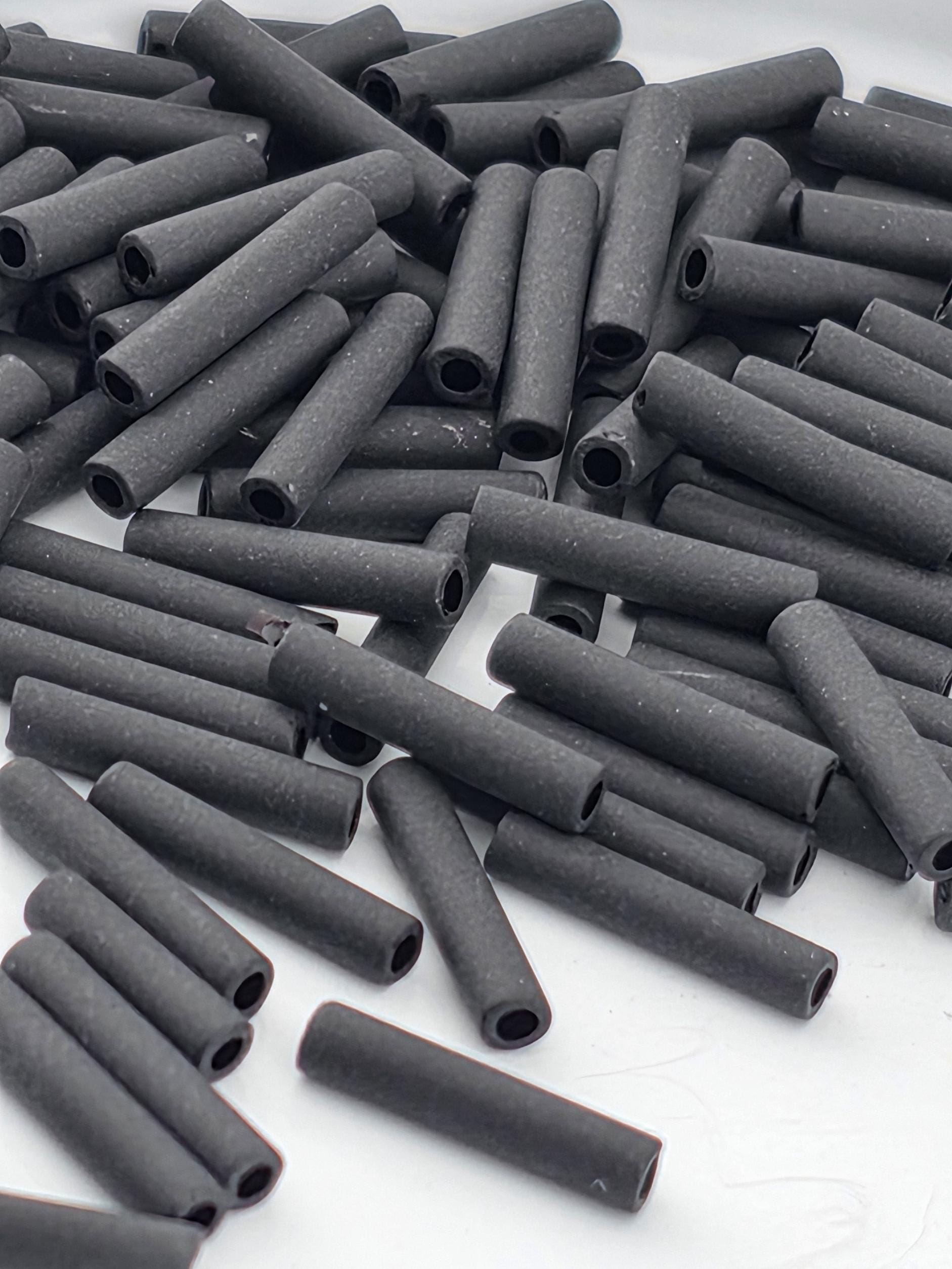 numerous black cylindrical objects, possibly metal pipes or tubes, scattered across a white surface.