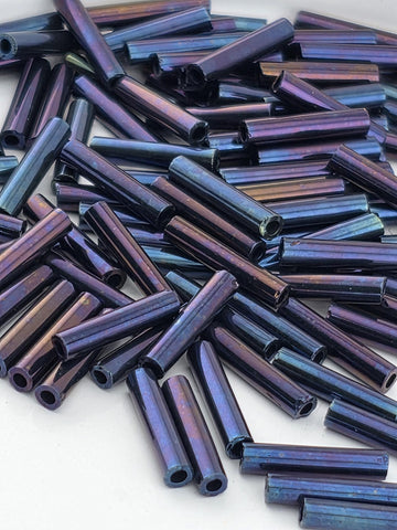 a close-up view of numerous metallic rods or tubes in various shades of blue and purple, scattered across a surface.