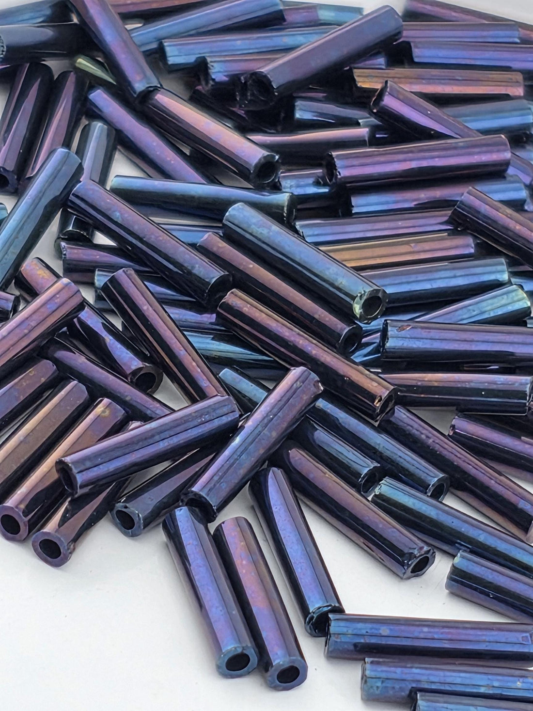 a close-up view of numerous metallic rods or tubes in various shades of blue and purple, scattered across a surface.