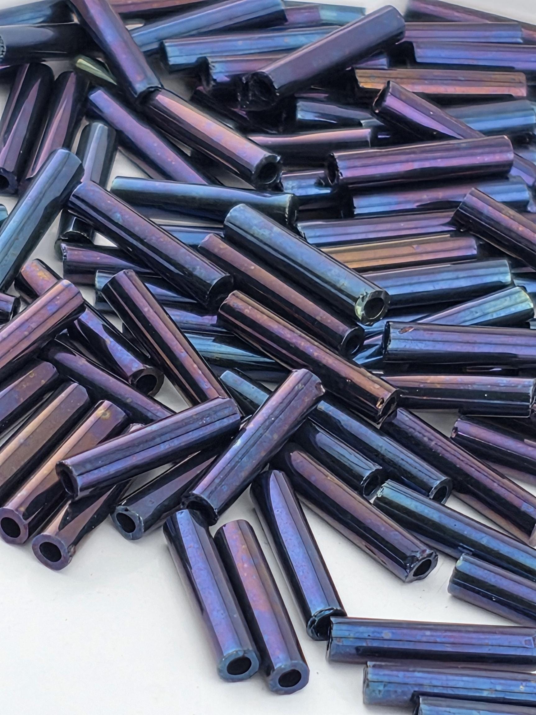 a close-up view of numerous metallic rods or tubes in various shades of blue and purple, scattered across a surface.