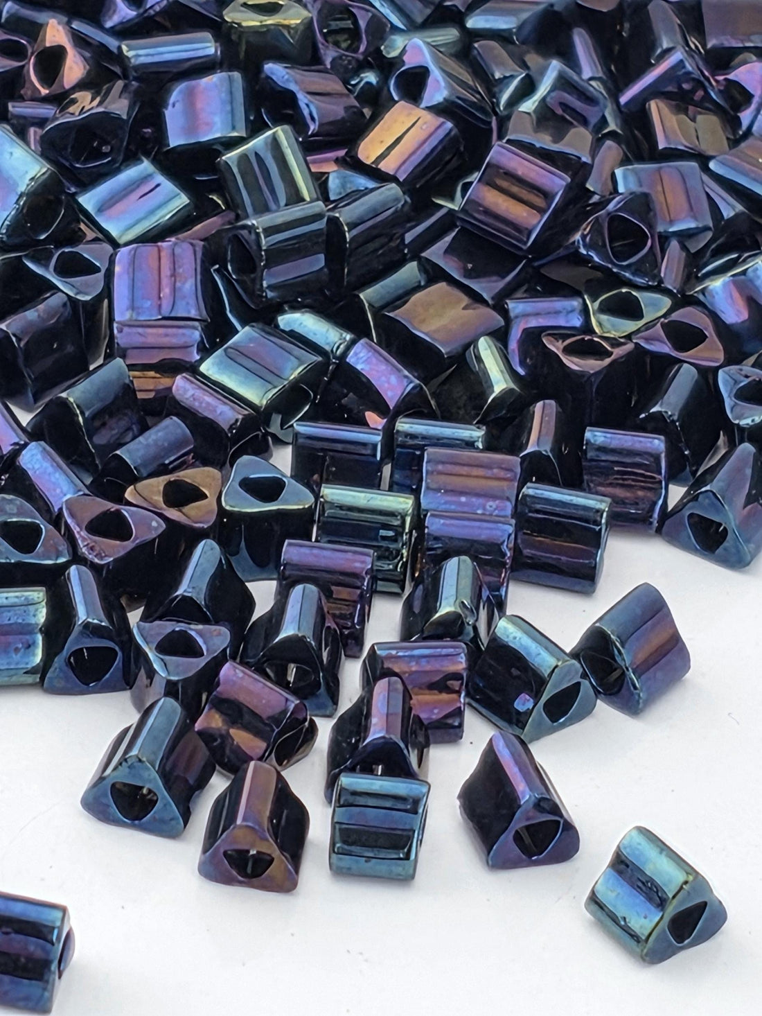 a close-up view of numerous small, metallic beads in various shades of blue and purple, scattered across a surface.