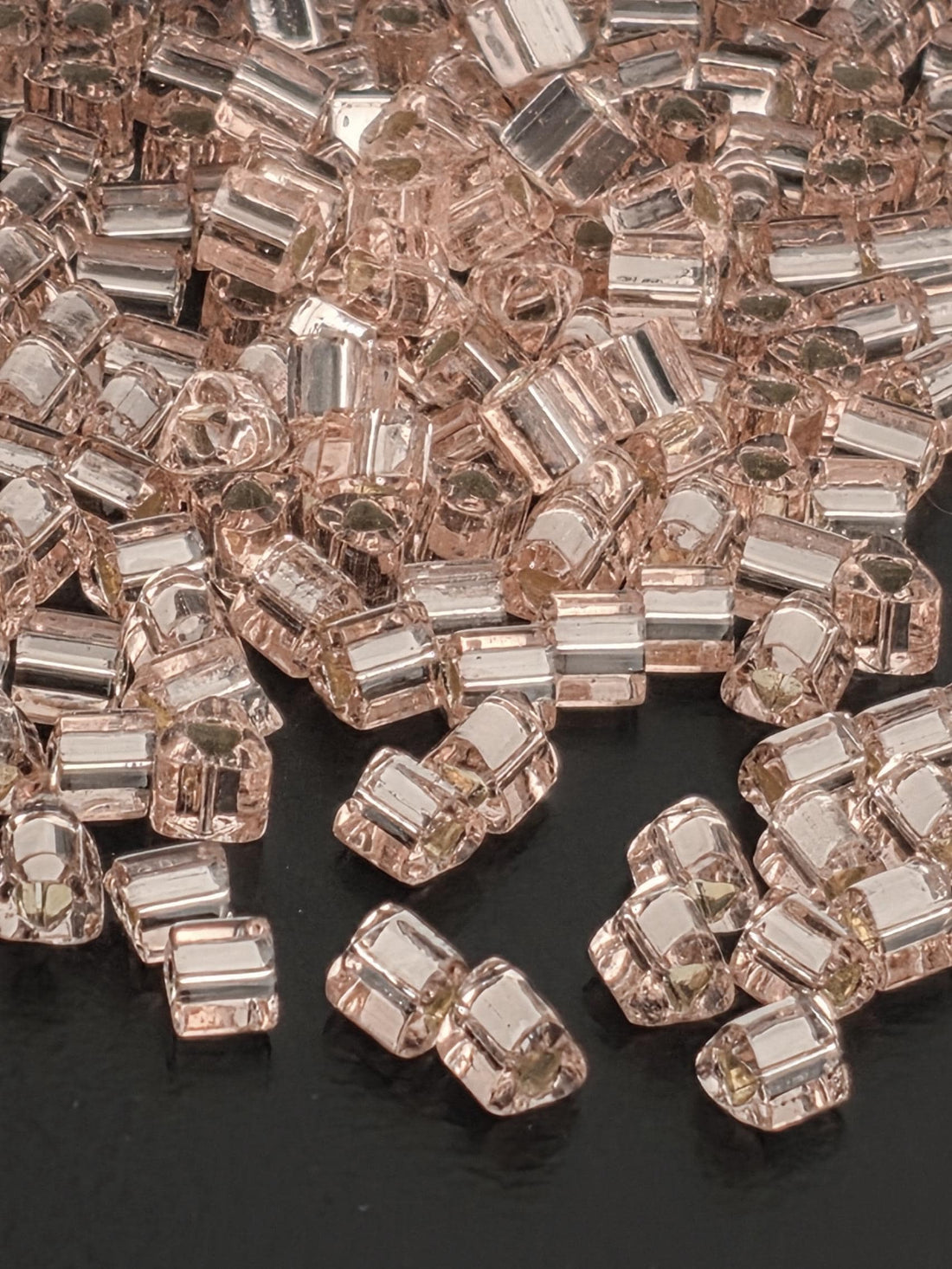 numerous small, clear, and shiny glass beads scattered across a dark background.