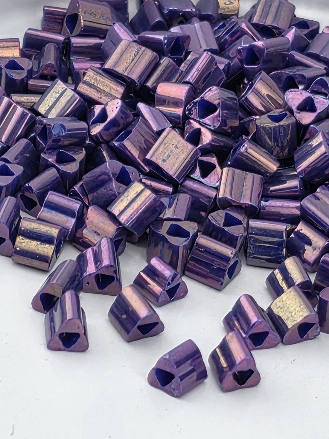 a pile of small, purple and gold-colored metal pieces scattered on a white surface.