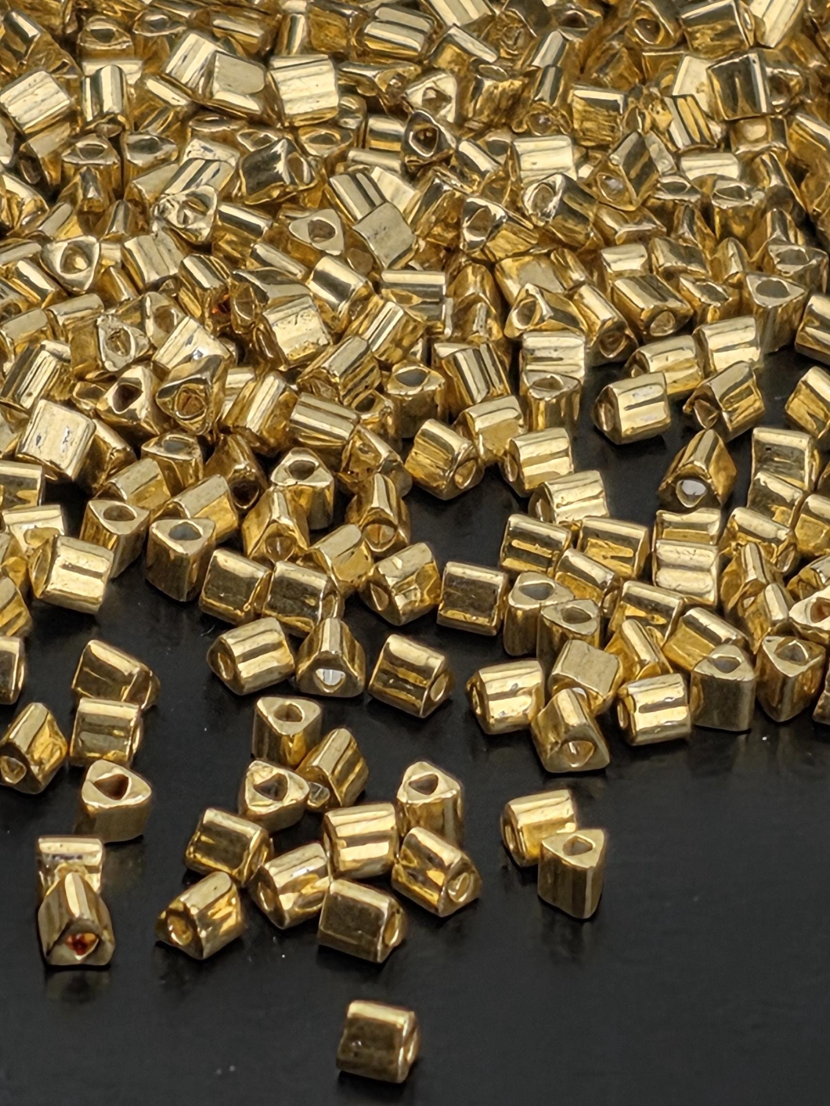 a close-up view of numerous small, shiny gold-colored metal pieces scattered across a dark background.