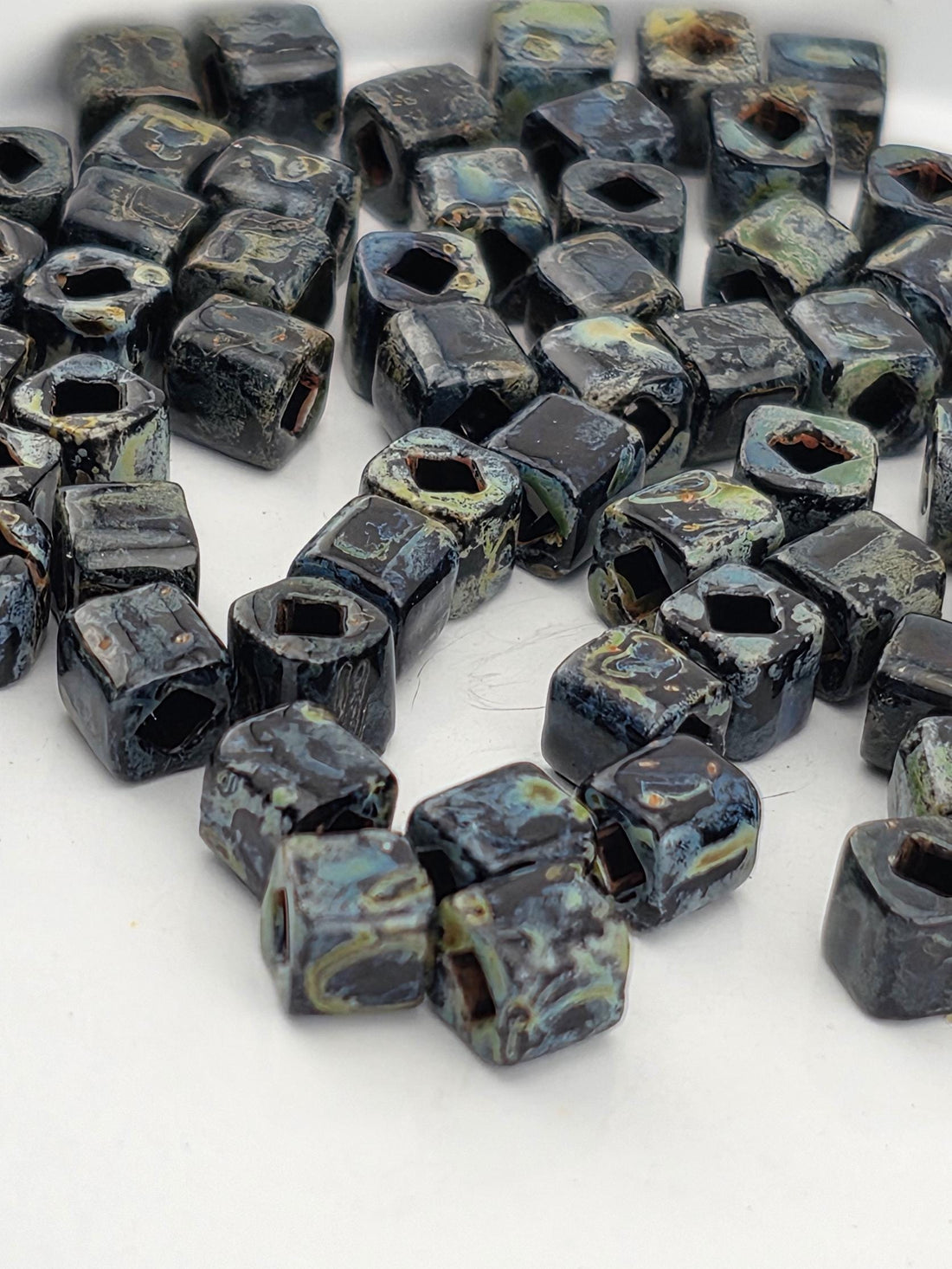 a collection of small, square-shaped objects with a dark, textured appearance. The objects are scattered across a white surface, creating a visually striking contrast.