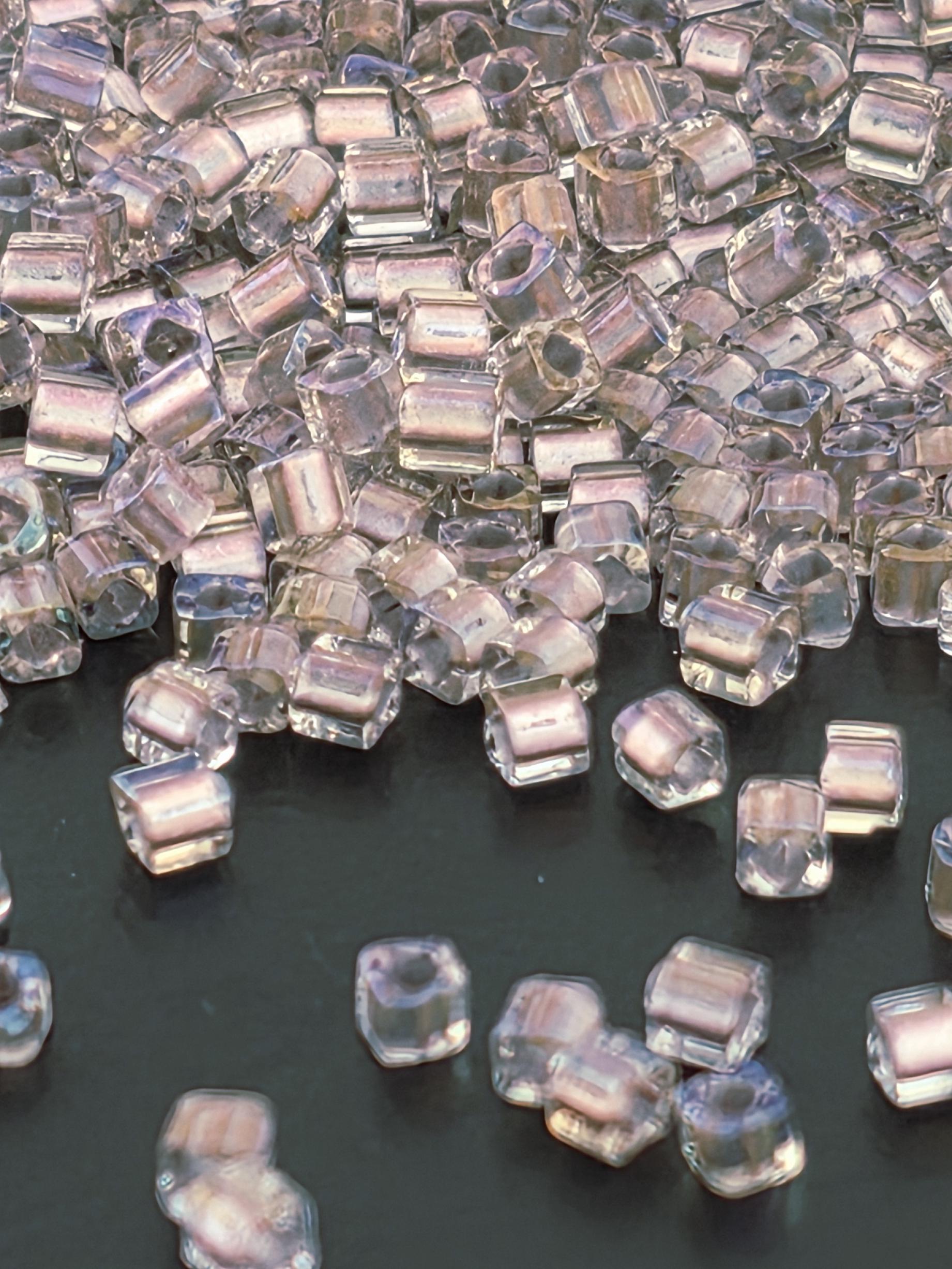 a collection of clear, transparent crystal beads or stones scattered on a dark surface.