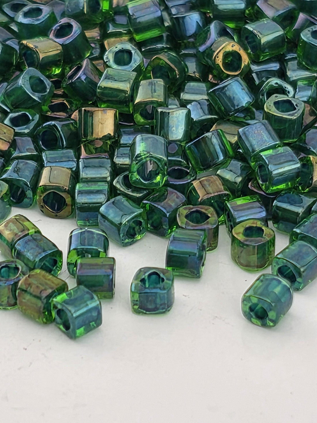 a close-up view of numerous green glass beads scattered on a white surface.