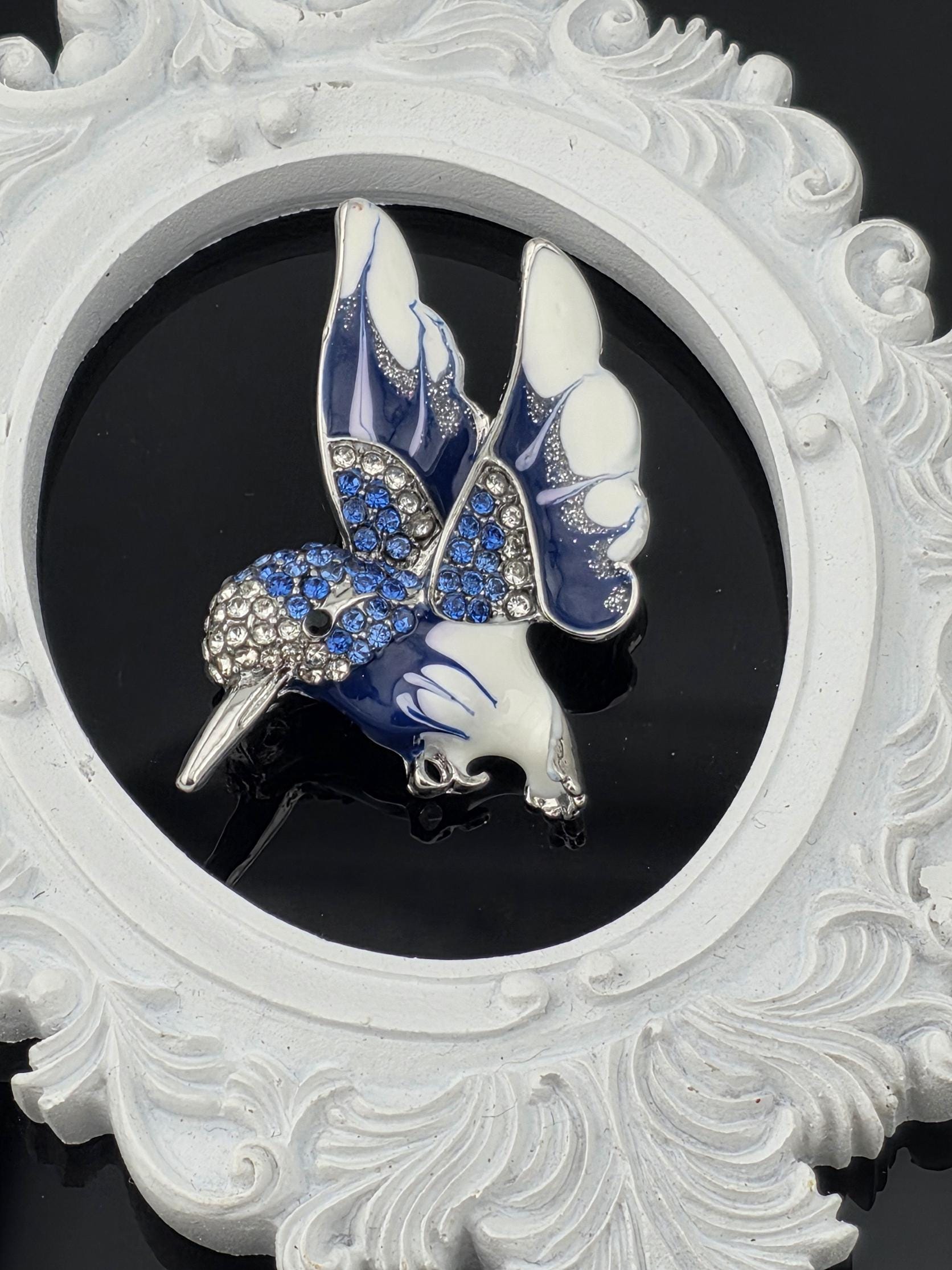A decorative white frame with a blue and white butterfly brooch in the center.