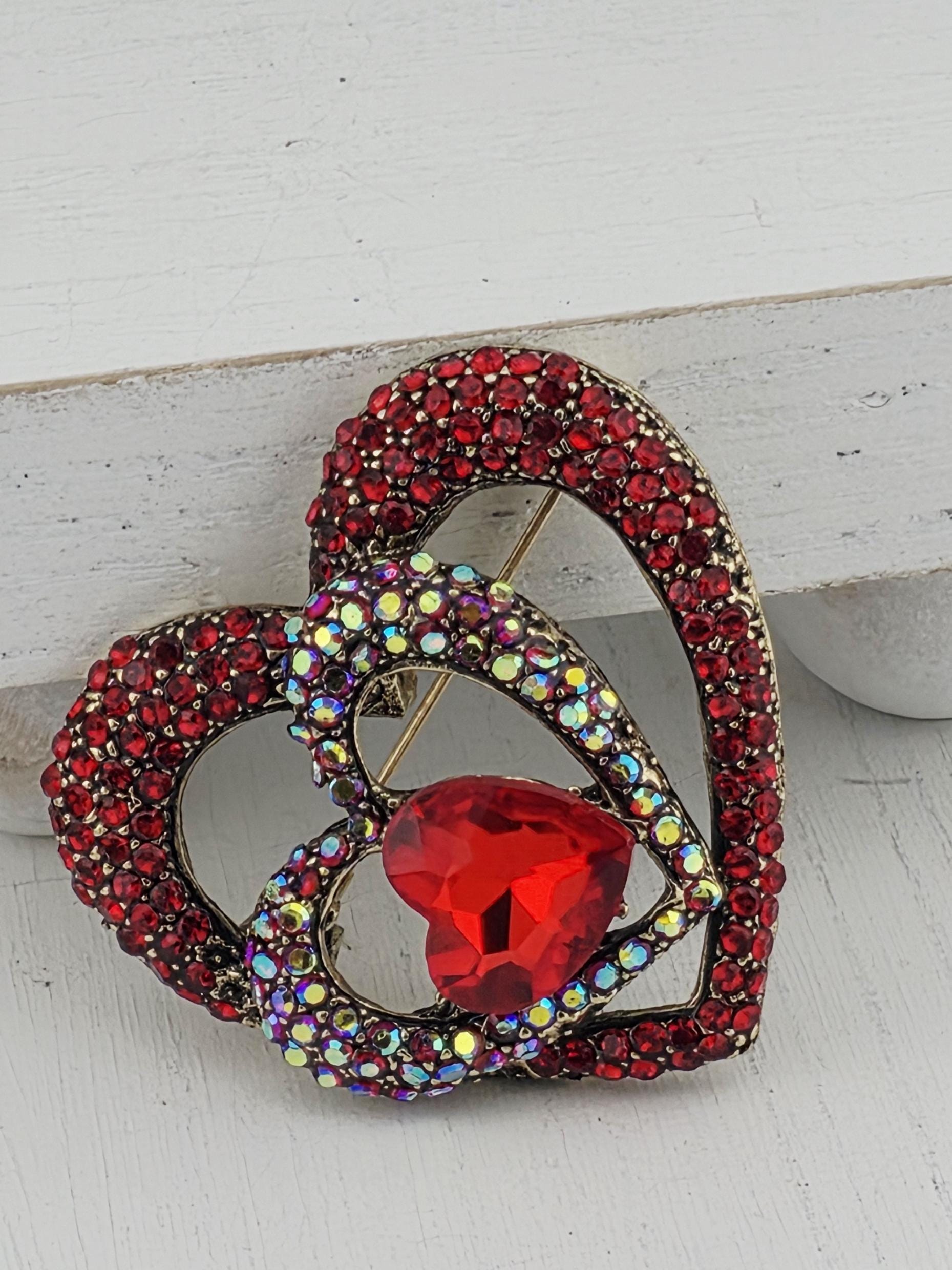 A decorative brooch with a heart-shaped gemstone and a sparkling crystal design.