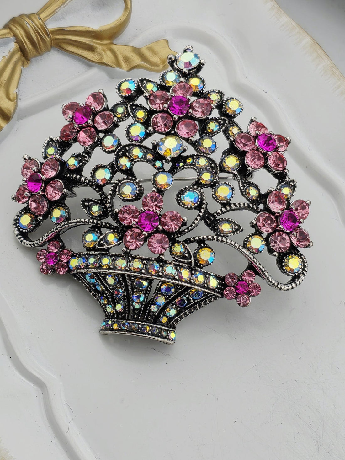 A decorative brooch with a floral design and sparkling rhinestones in various colors, including pink, purple, and blue.
