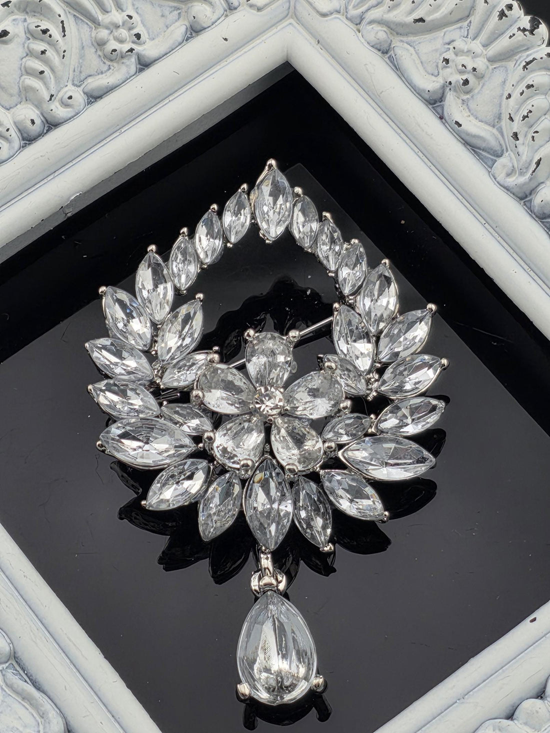A close-up view of a decorative piece featuring a large, intricate arrangement of clear, sparkling crystals or gemstones set within a frame.