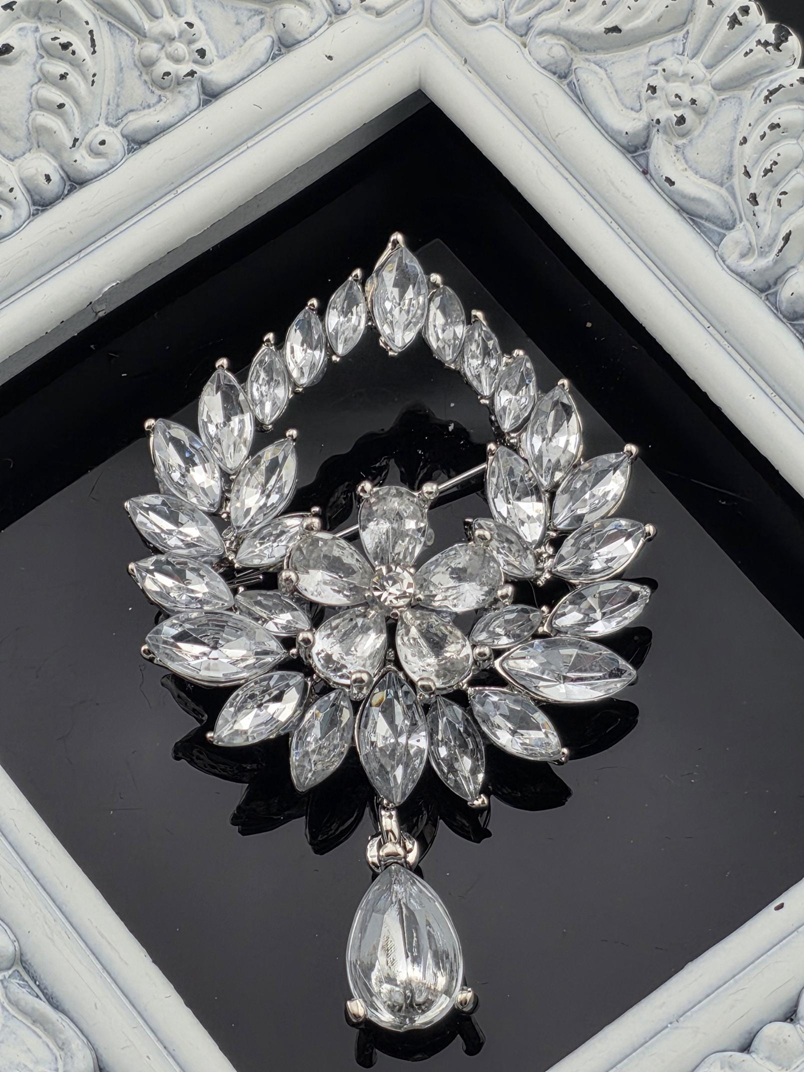 A close-up view of a decorative piece featuring a large, intricate arrangement of clear, sparkling crystals or gemstones set within a frame.