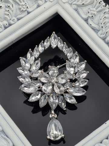 A close-up view of a decorative piece featuring a large, intricate arrangement of clear, sparkling crystals or gemstones set within a frame.