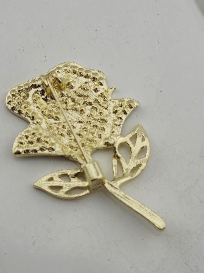 A gold-colored pin in the shape of a flower, with a detailed design and a metallic appearance.