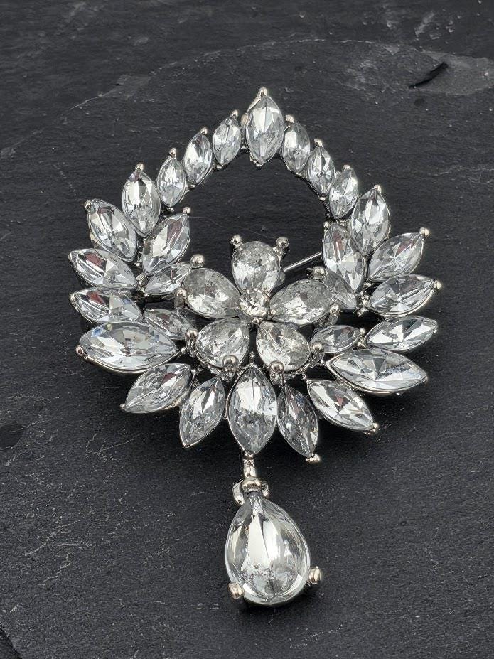 A brooch with a large, sparkling crystal design, featuring a central flower-like shape surrounded by numerous smaller crystals.