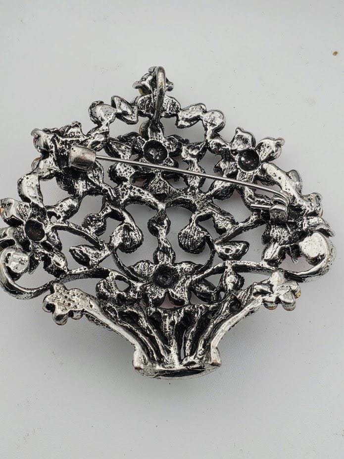 A decorative metal pin or brooch with an intricate floral design.