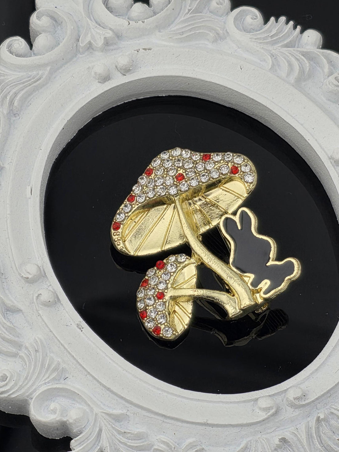 A decorative gold and diamond-encrusted shoe is displayed against a black background, framed by an ornate white border.