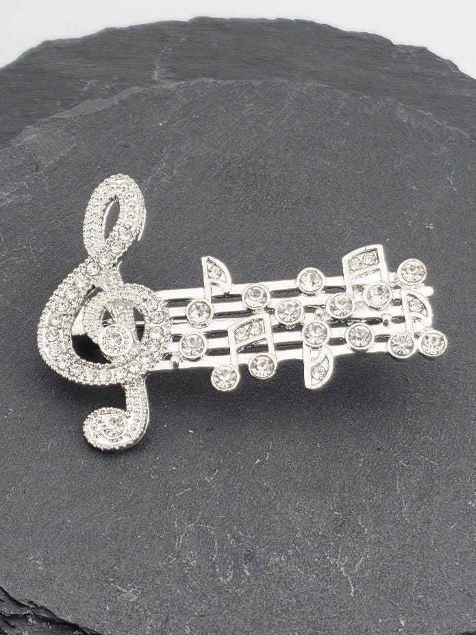 a close-up view of a piece of jewelry, possibly a necklace or bracelet, adorned with numerous sparkling diamonds. The jewelry appears to be a decorative piece, possibly a brooch or pendant, with intricate designs and patterns. The background is dark, which contrasts with the sparkling diamonds and highlights the details of the jewelry.