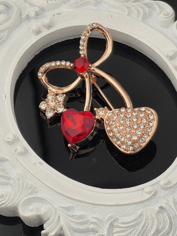 A close-up of a decorative piece featuring a heart-shaped gemstone surrounded by smaller gemstones and a bow-shaped element.
