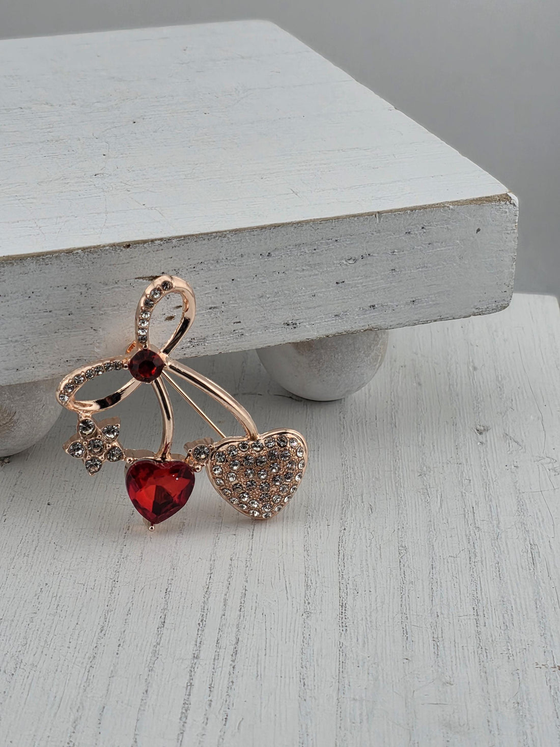 A close-up of a decorative piece featuring a heart-shaped gemstone surrounded by smaller gemstones and a bow-shaped element.