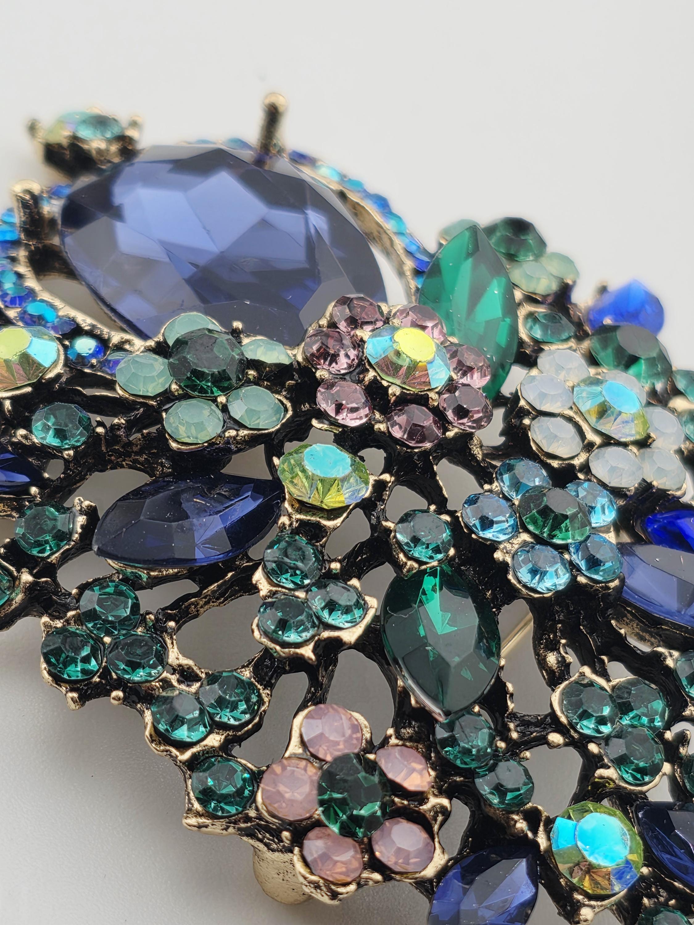 A close-up image of a decorative piece of jewelry, featuring a variety of colorful gemstones and metallic elements.