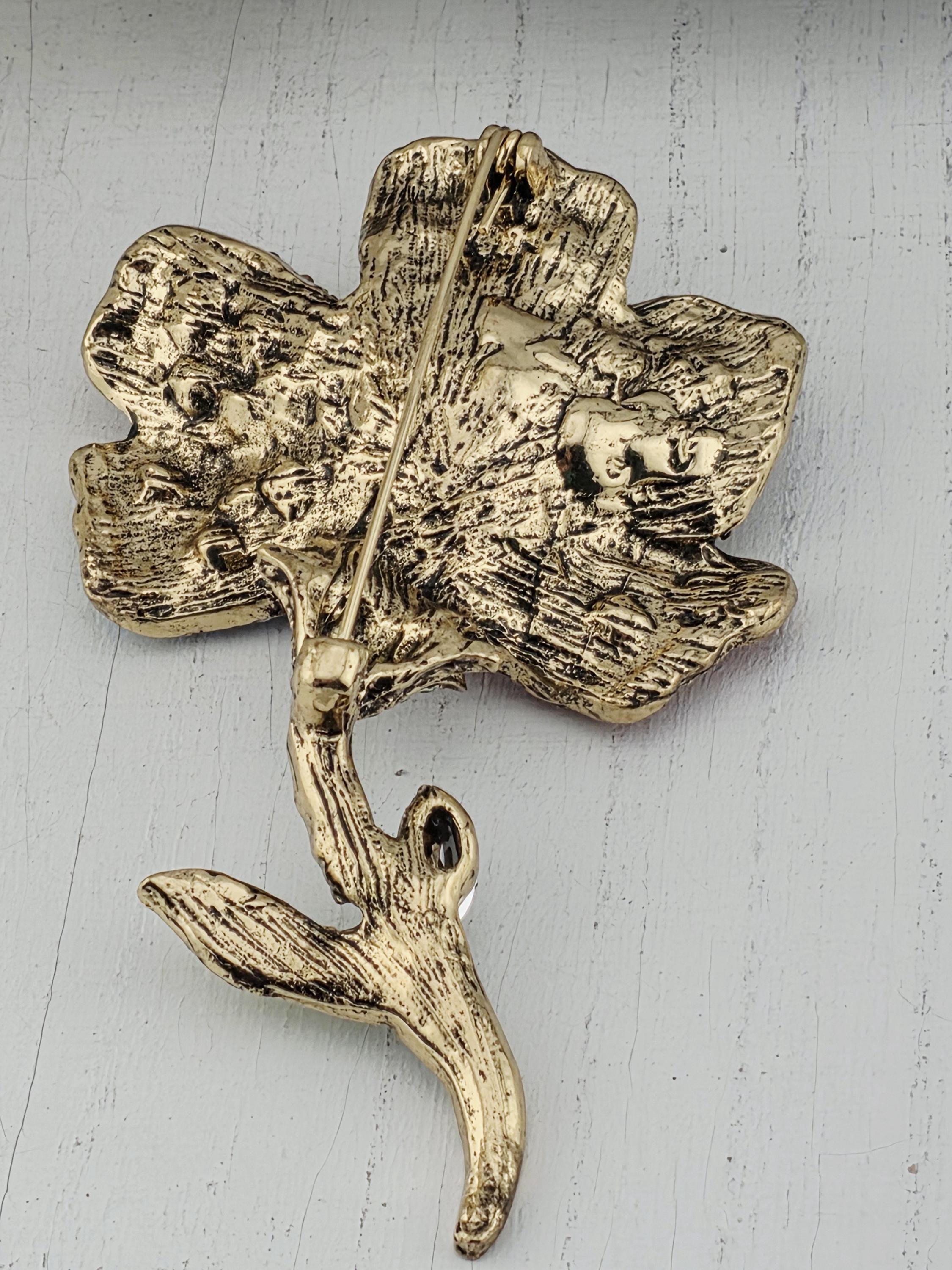 A close-up image of a decorative golden leaf-shaped brooch or badge.