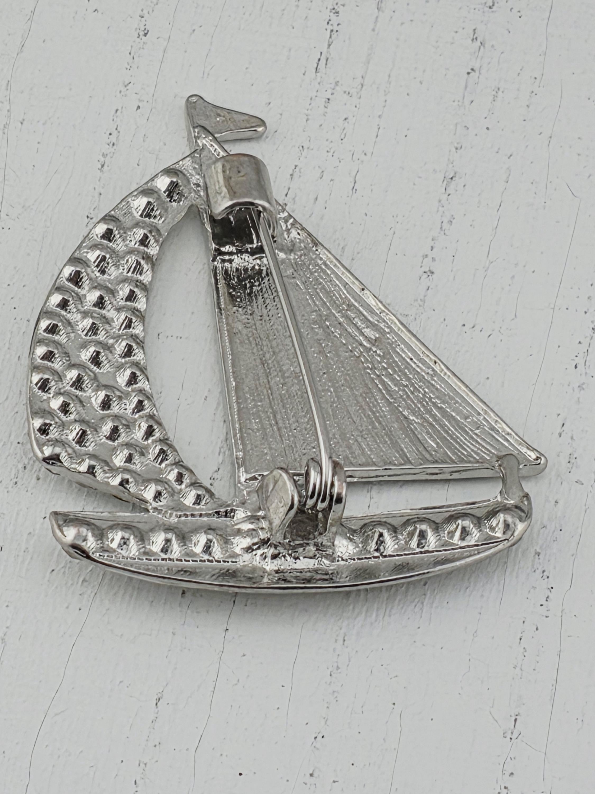 A silver-colored metal pin or brooch with a unique, textured design.