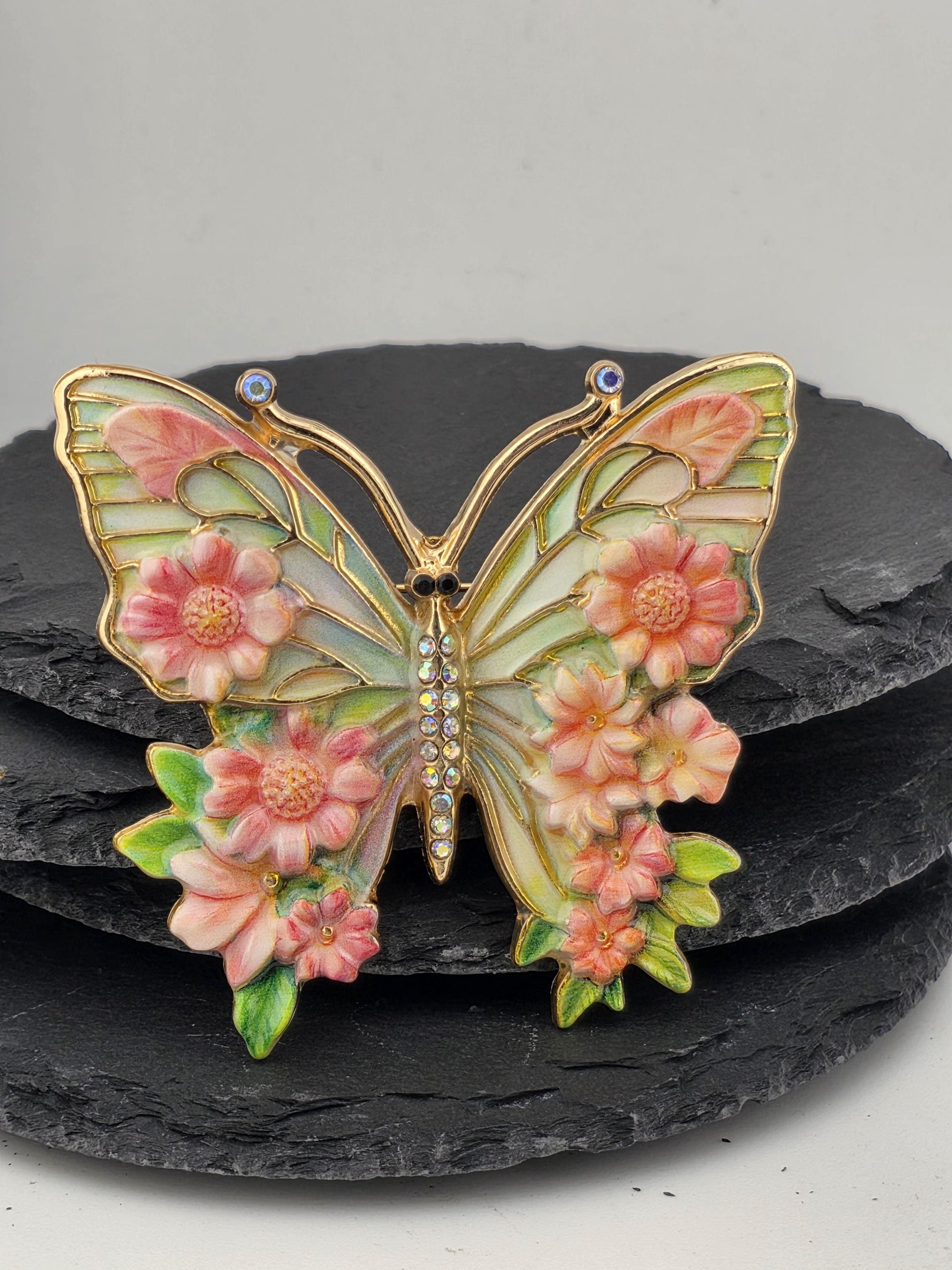 A decorative butterfly brooch with a floral design and sparkling gemstones.