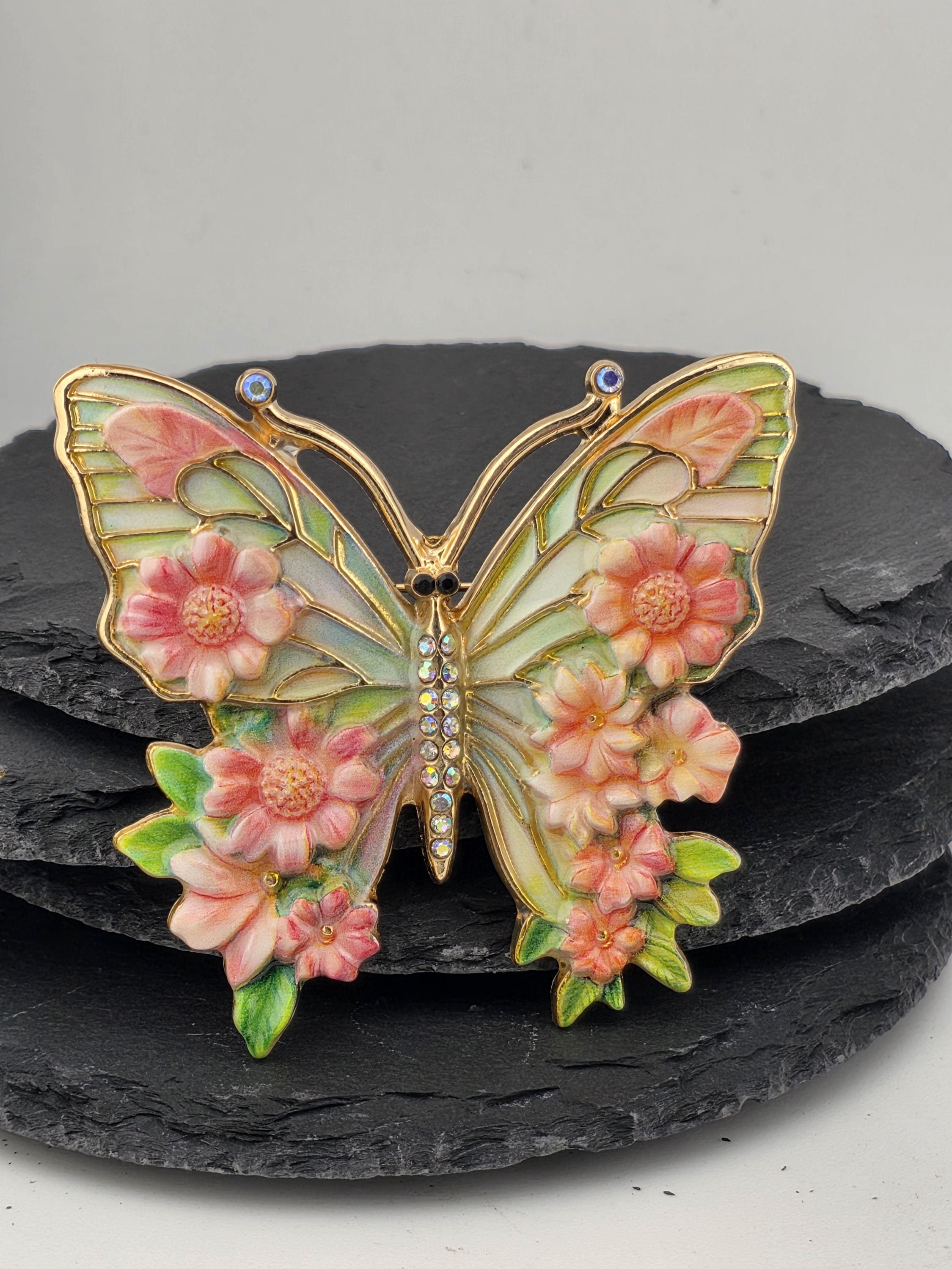 A decorative butterfly brooch with a floral design and sparkling gemstones.