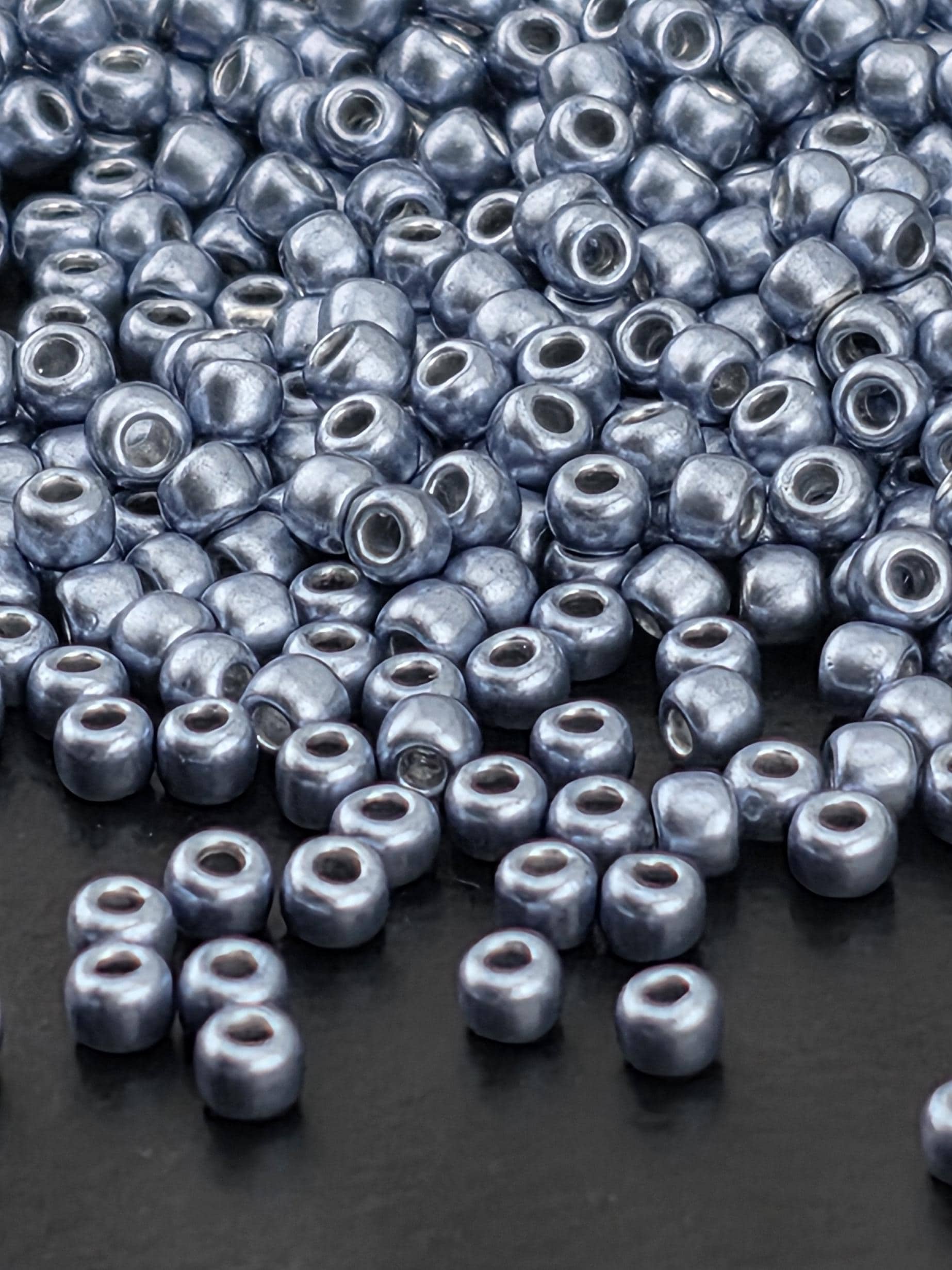 a close-up view of numerous silver-colored beads scattered on a dark surface.