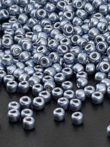 a close-up view of numerous silver-colored beads scattered on a dark surface.